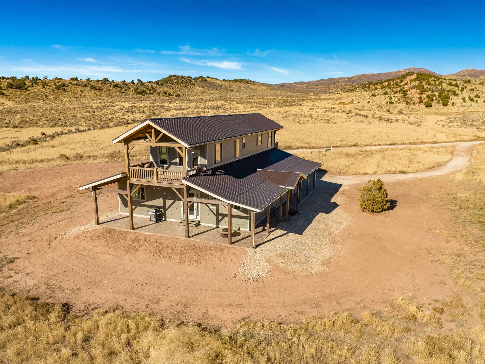 Two-story residence featuring a covered patio, upper-level balconies, and exposed wood beam construction