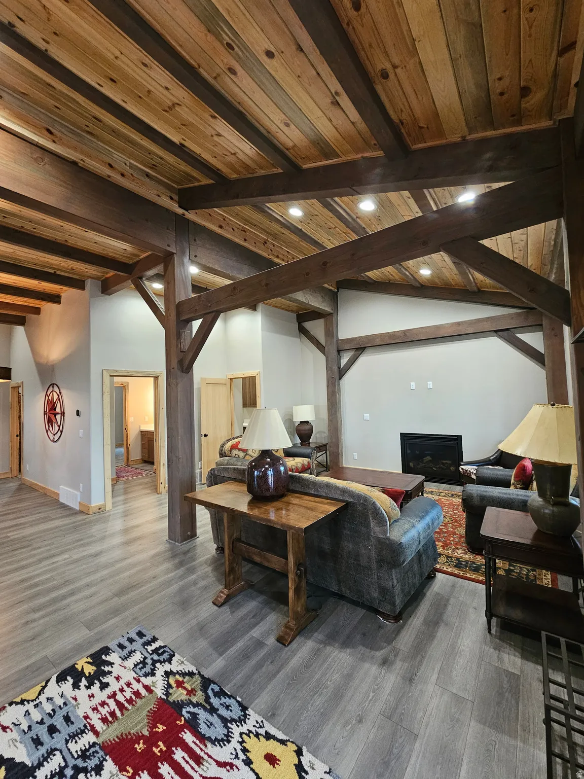 Open living space featuring wood-finish flooring and exposed wood beams & fireplace