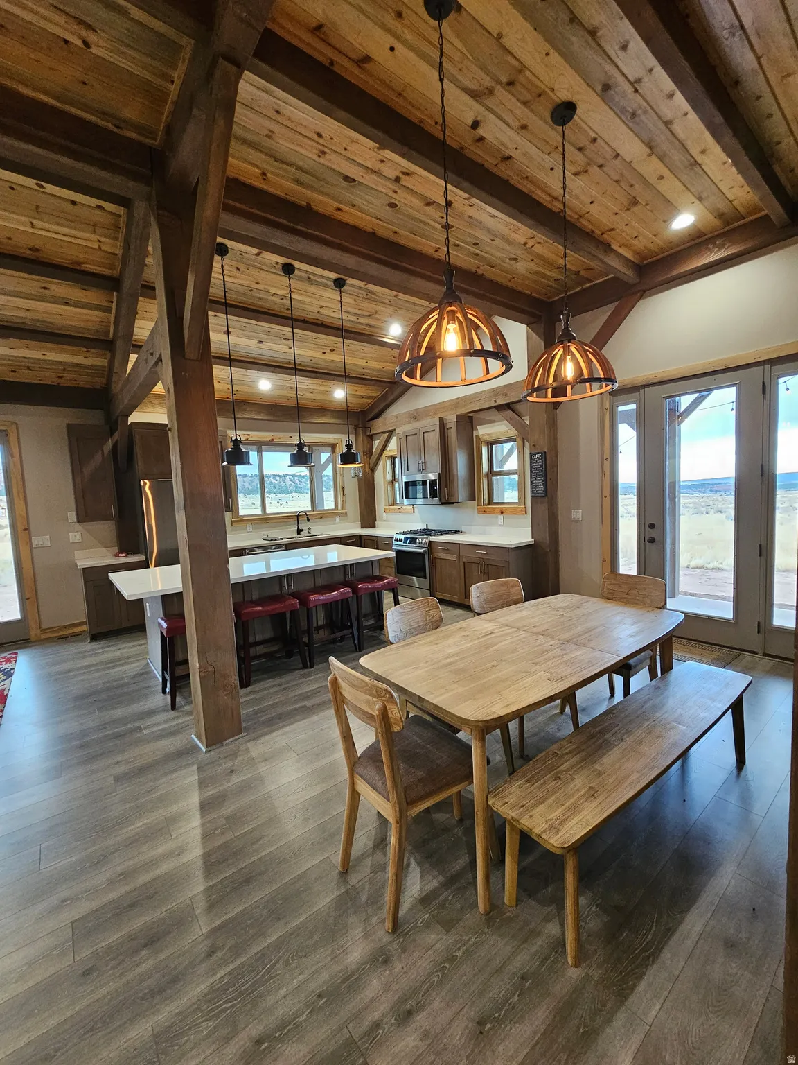 Open-concept living space with exposed wood beam ceiling, wood-finish flooring, and recessed lighting