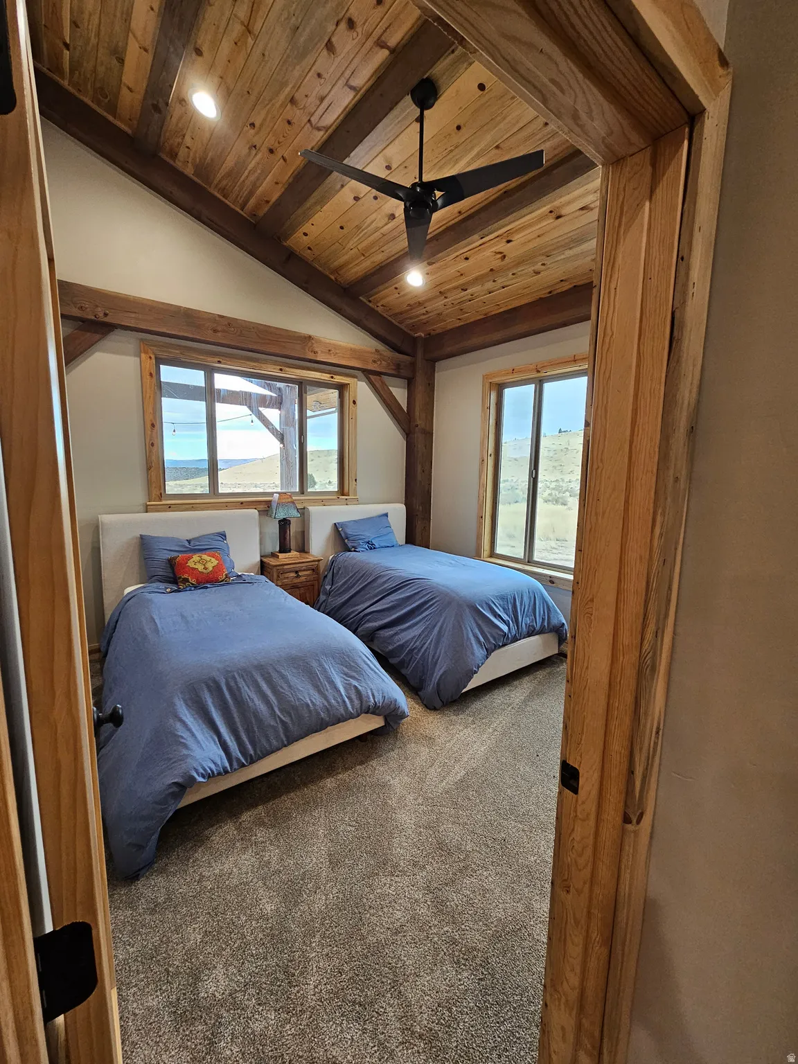 Bedroom with vaulted wood ceiling with exposed wood beams and a ceiling fan