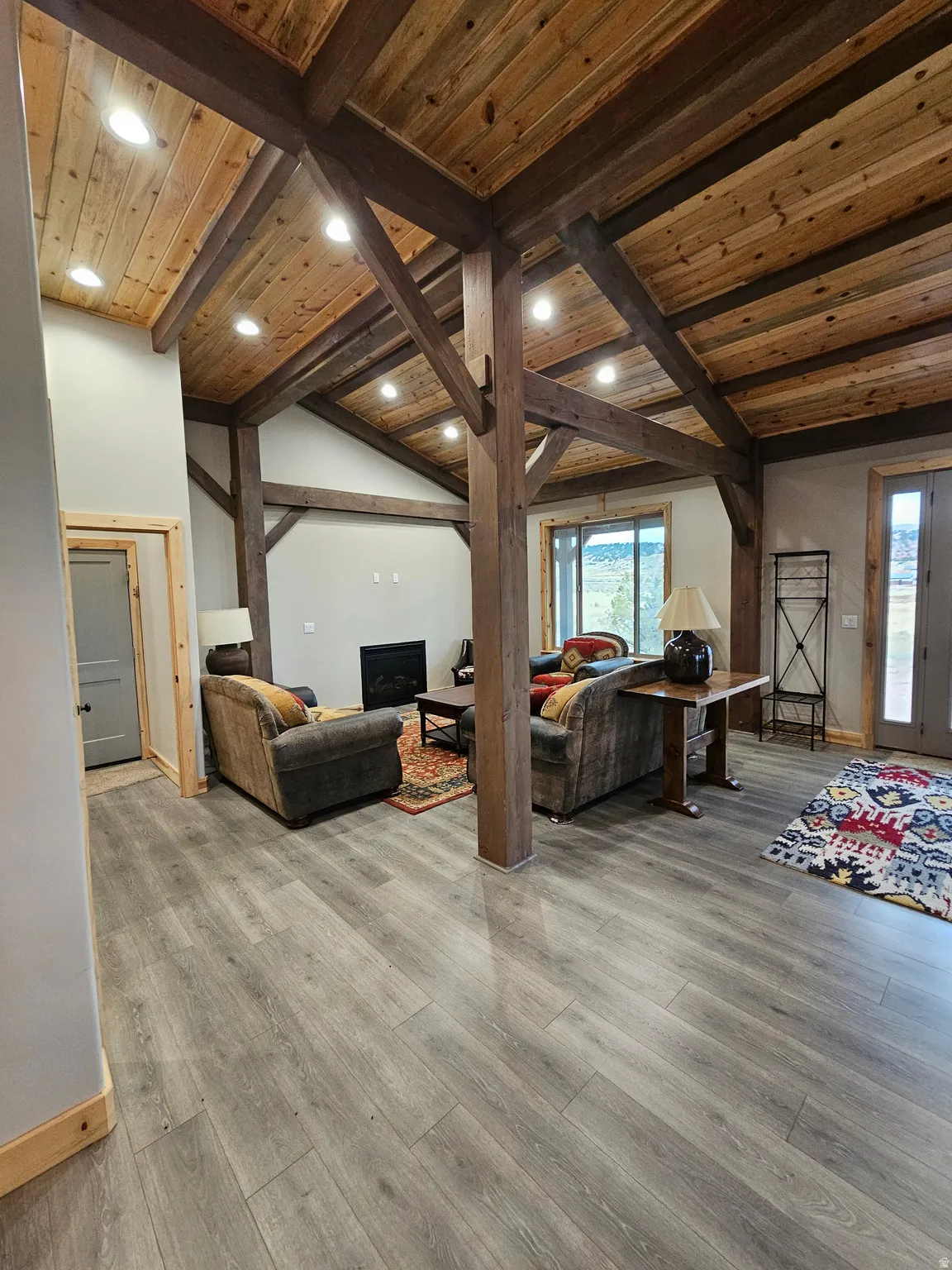 Open living space featuring wood-finish flooring and exposed wood beams & fireplace