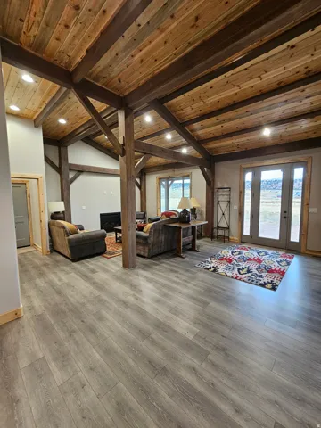 Open living space featuring wood-finish flooring and exposed wood beams & fireplace