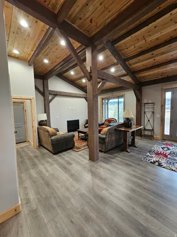 Open living space featuring wood-finish flooring and exposed wood beams & fireplace