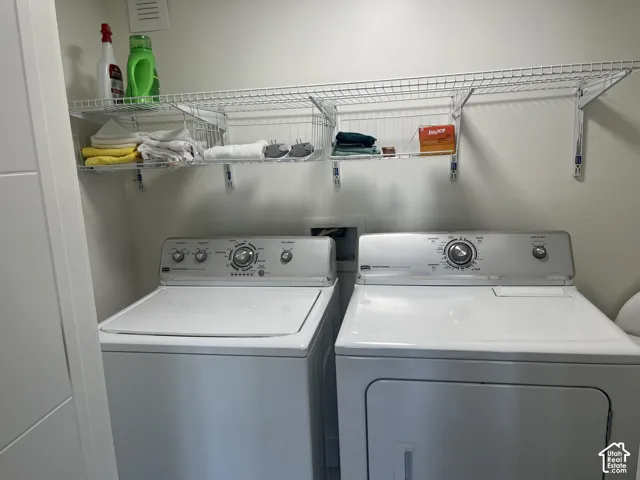 Dedicated laundry area featuring a top-load washer, a front-load dryer, and a wall-mounted wire shelving system