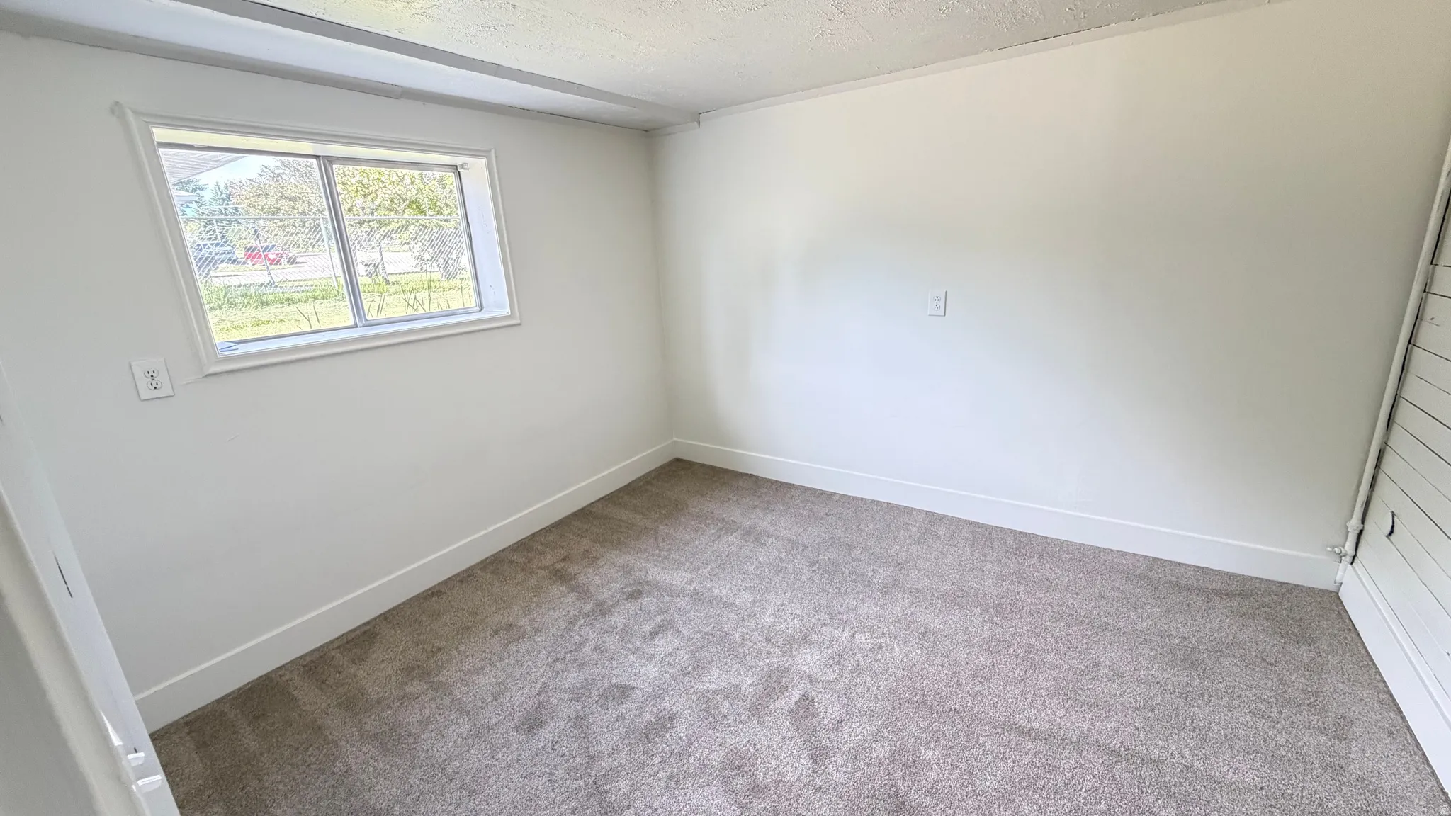Room featuring a neutral carpet, white walls, and a window with white trim