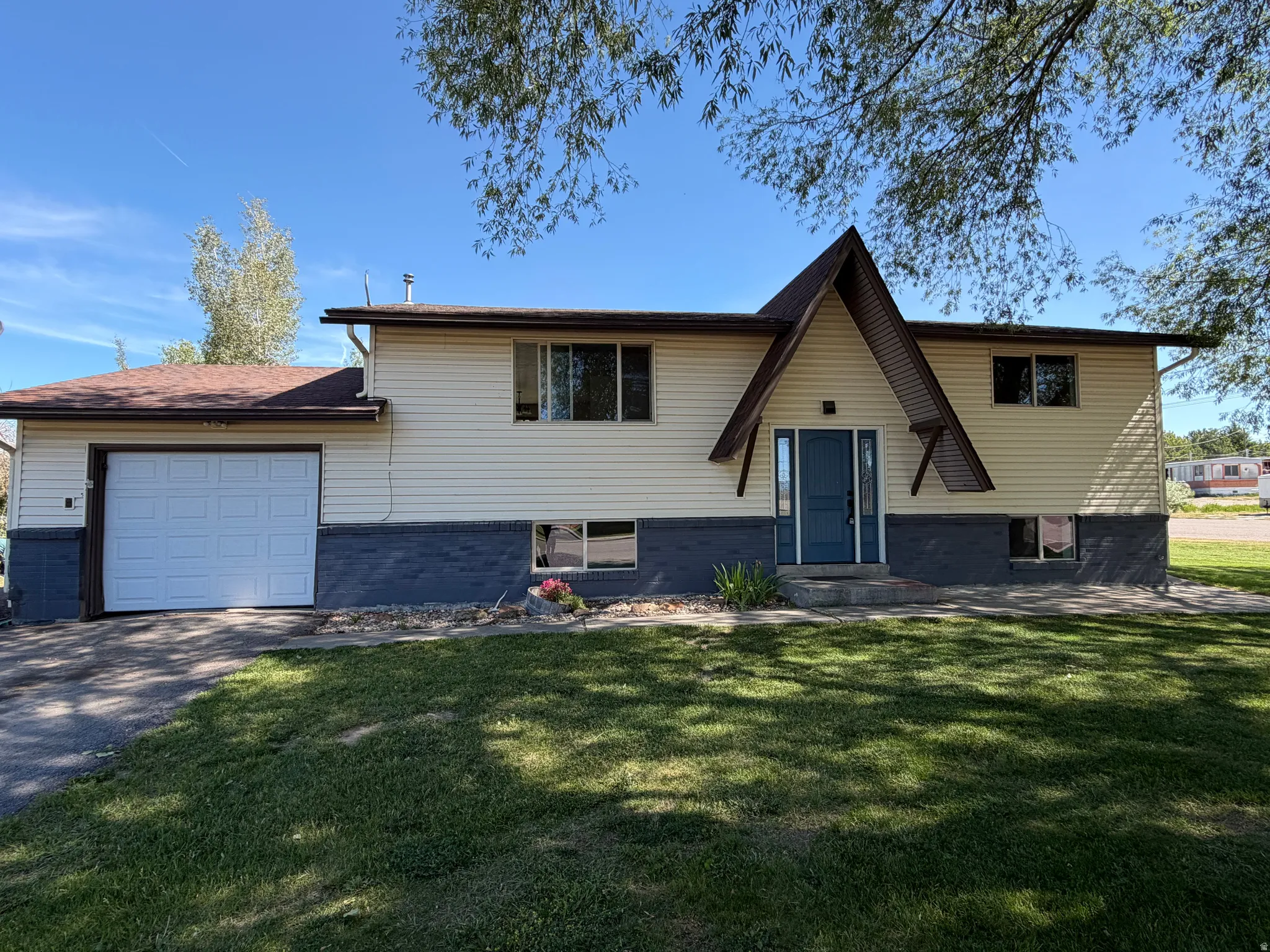 Split-level residence featuring a prominent A-frame entry, two-tone siding, an attached garage, and a concrete driveway