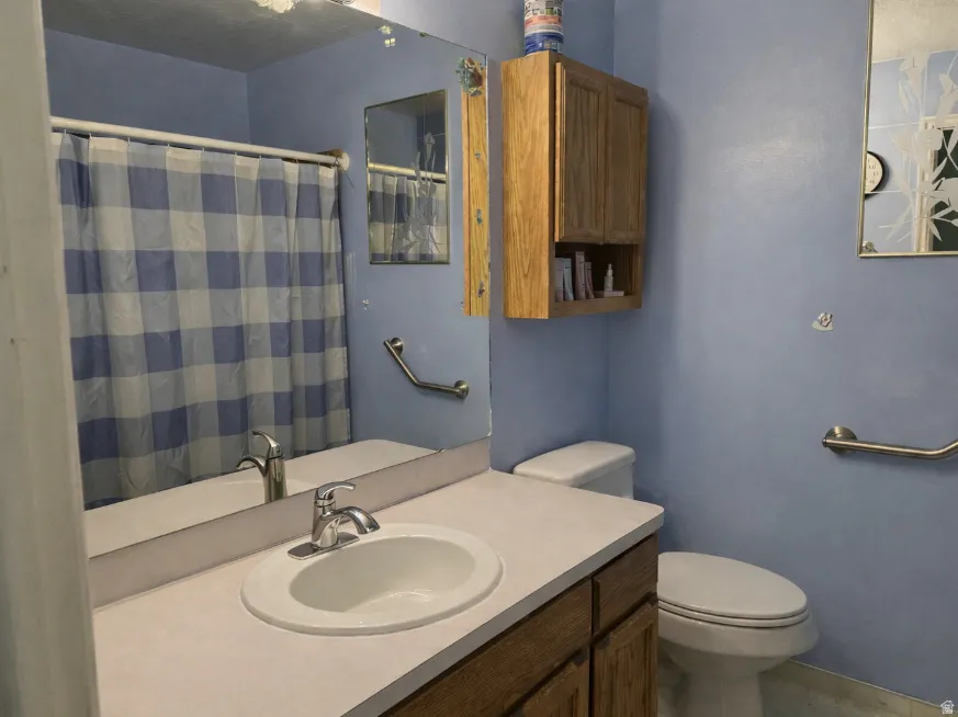 Bathroom featuring a single vanity with a white countertop, chrome faucet, and integrated sink