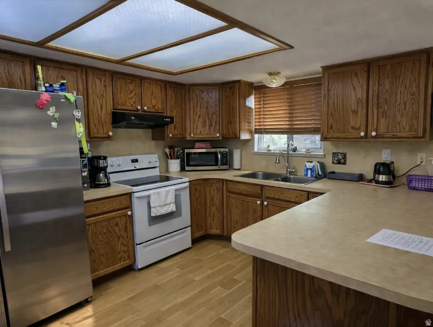 Kitchen featuring wood-finish cabinetry, light-toned countertops, and wood-finish flooring
