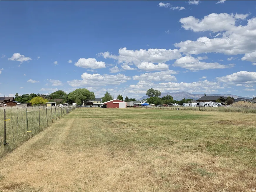 Expansive grassy lot with a wire fence lining the property boundary