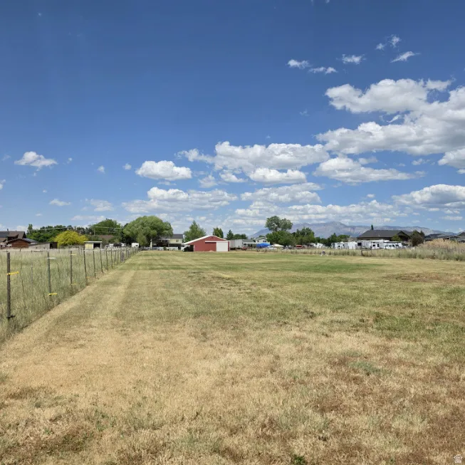Expansive open field featuring a partial perimeter fence and distant mountain range