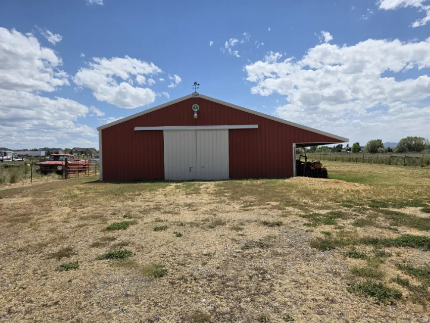 Red barn structure featuring a metal roof, white sliding doors, and a covered side extension