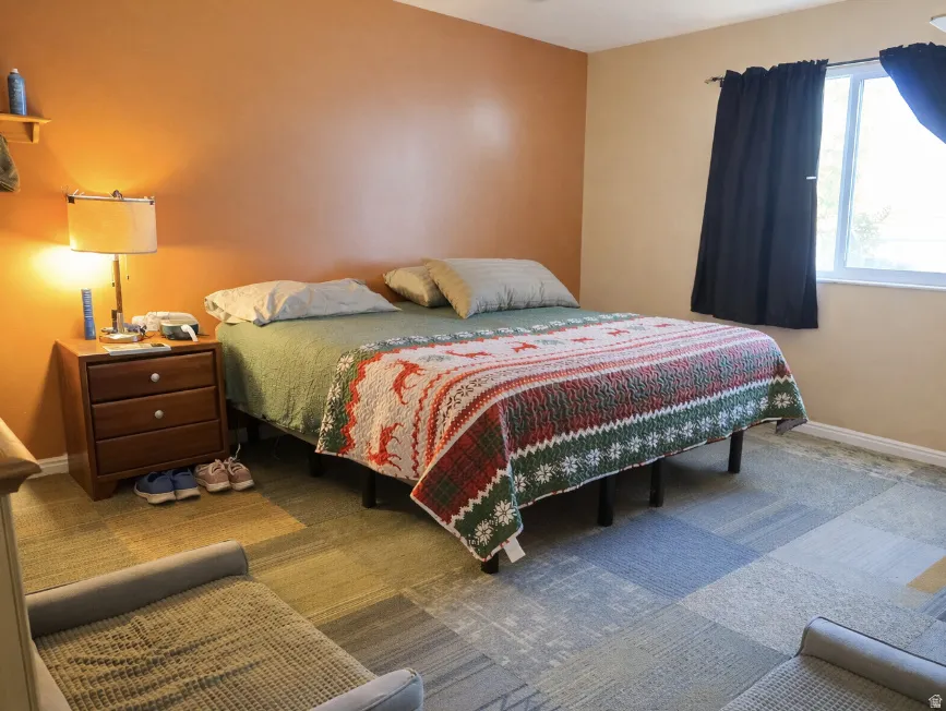 Bedroom featuring an accent wall, modular carpet tile flooring, and a single window with trim