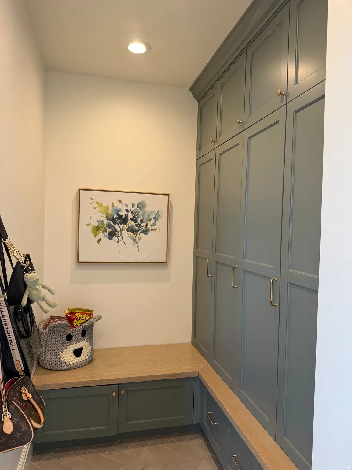 Built-in storage solutions featuring full-height cabinetry with crown molding, lower cabinetry, and an integrated wood-finish bench