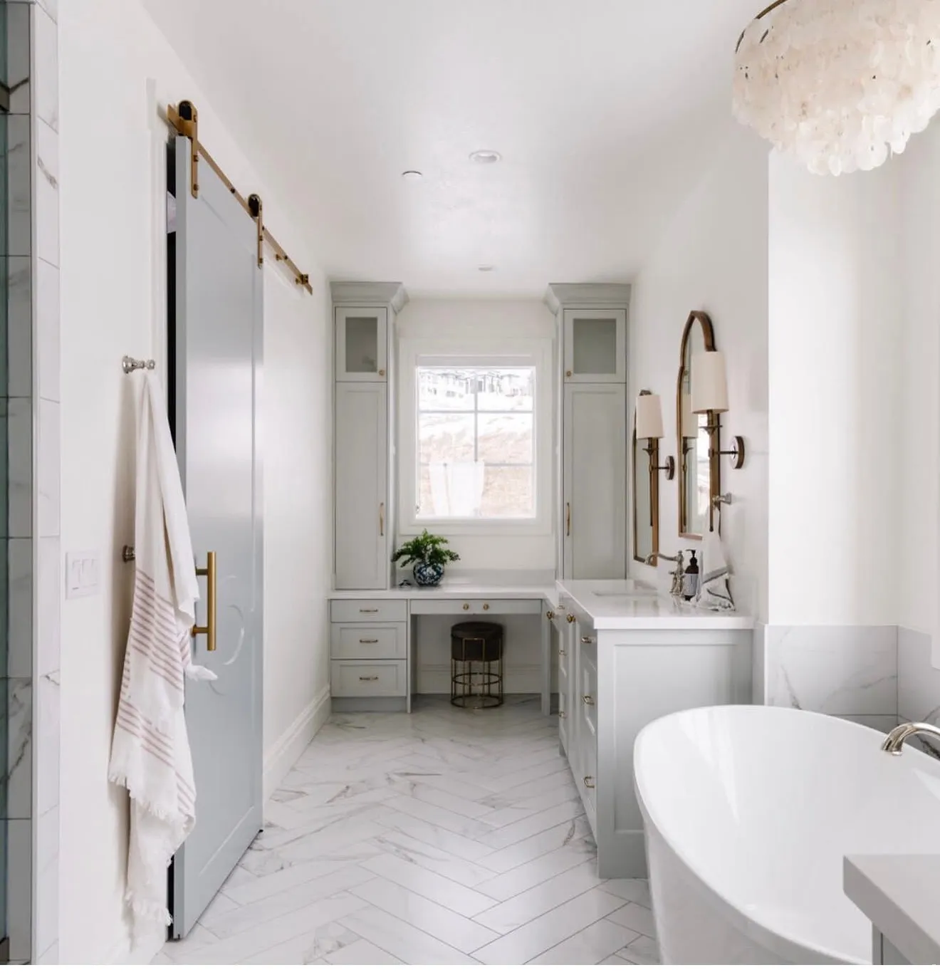 Bathroom featuring a freestanding tub, dual vanity with undermount sinks, and herringbone-patterned tile flooring