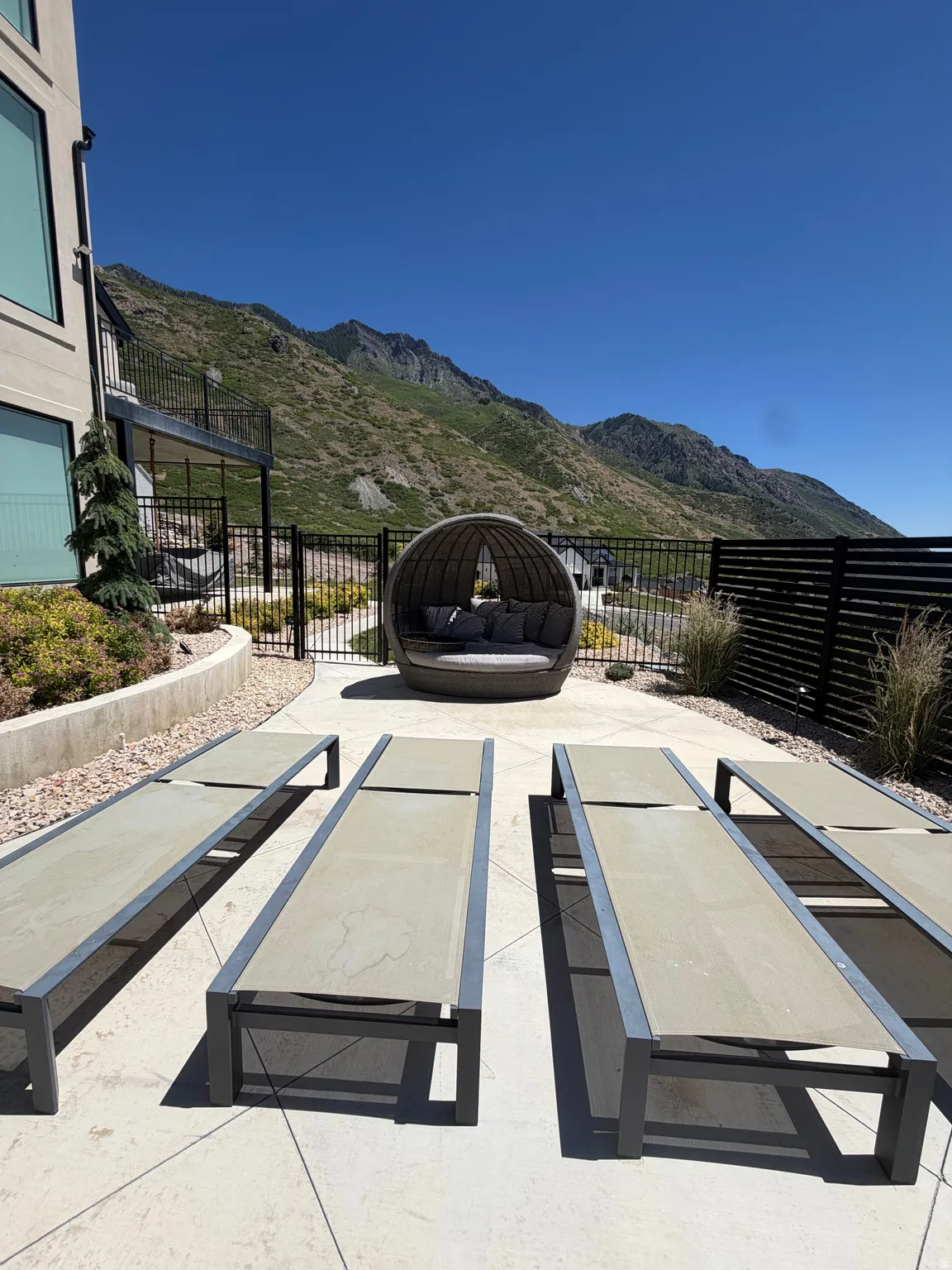 Expansive patio area featuring stamped concrete, multiple lounge chairs, and a circular daybed