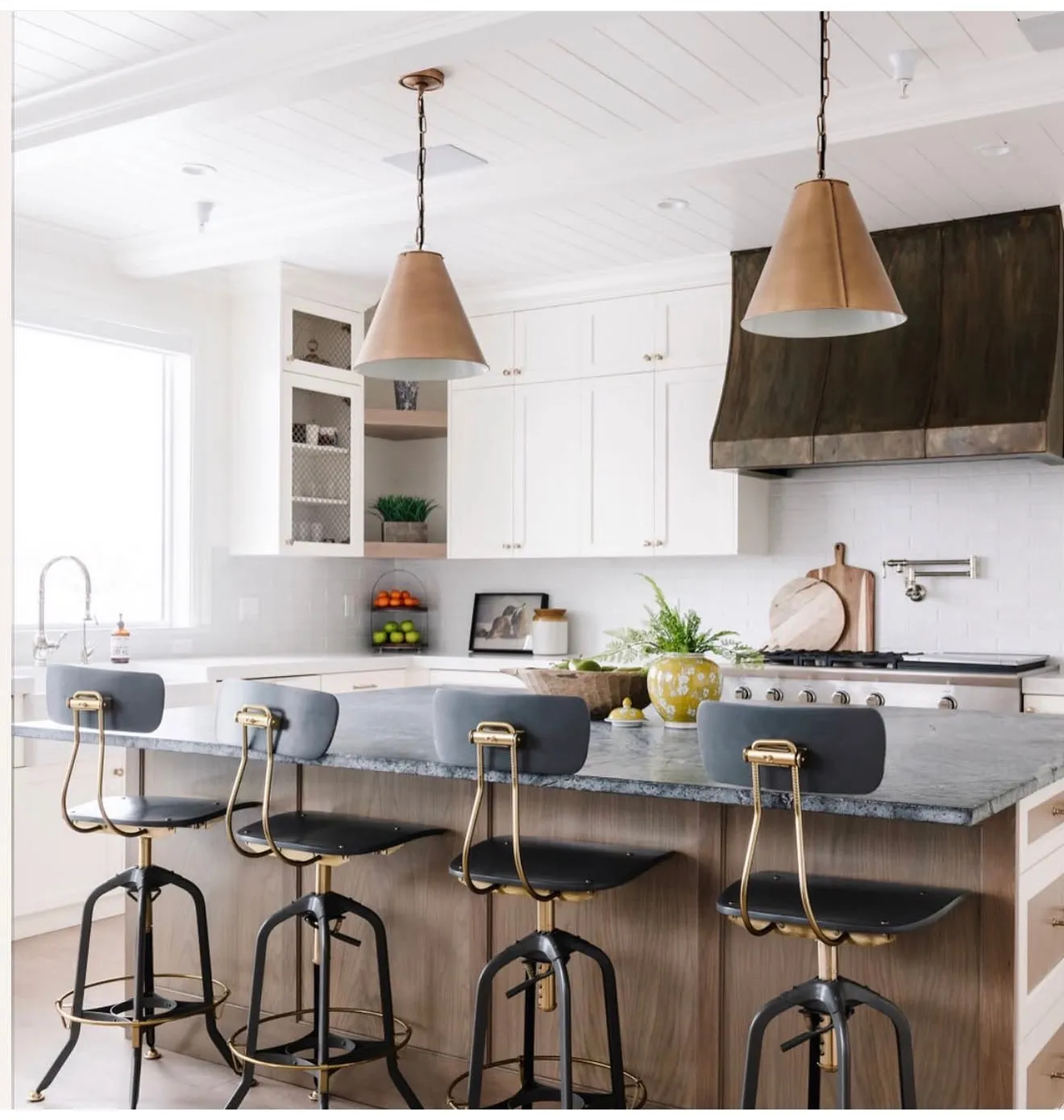 Kitchen island with a light wood-finish base, dark countertop, and four counter stools