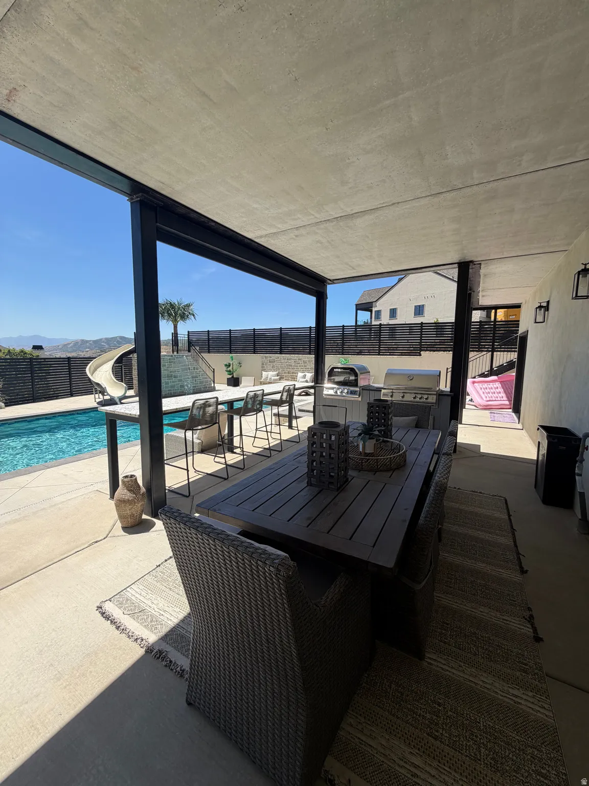 Covered patio with integrated outdoor kitchen, bar seating, and a refreshing pool