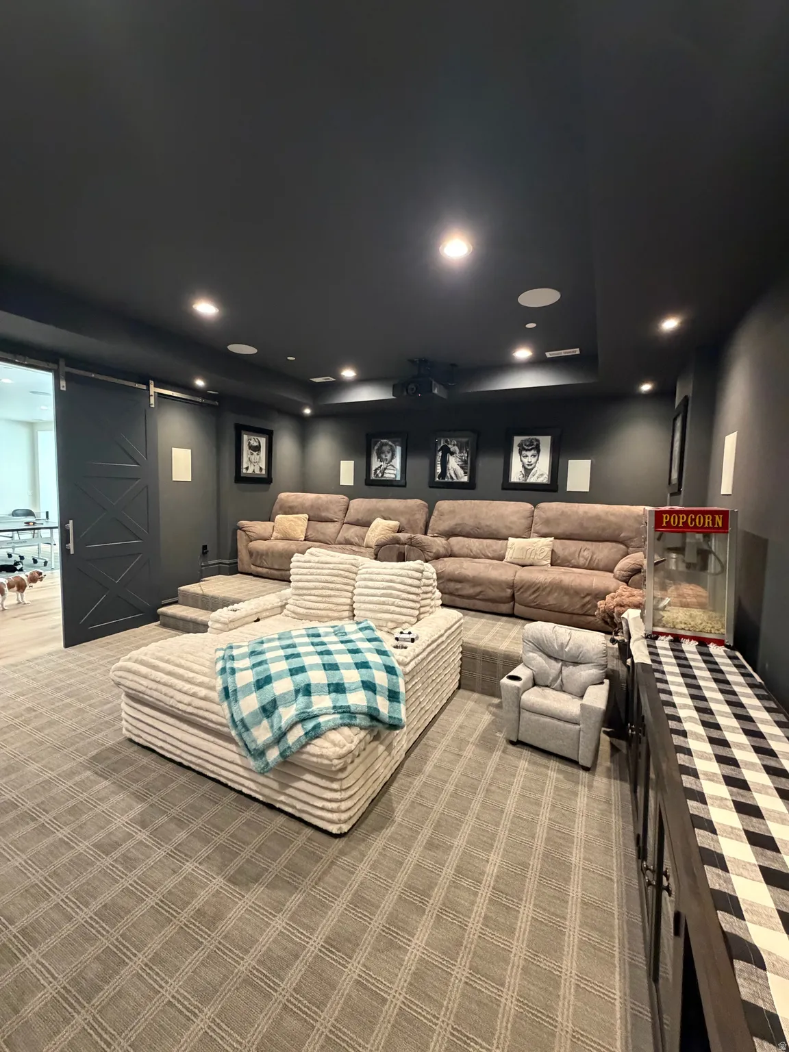 Dedicated media room featuring tiered seating, recessed lighting, and a barn door entry