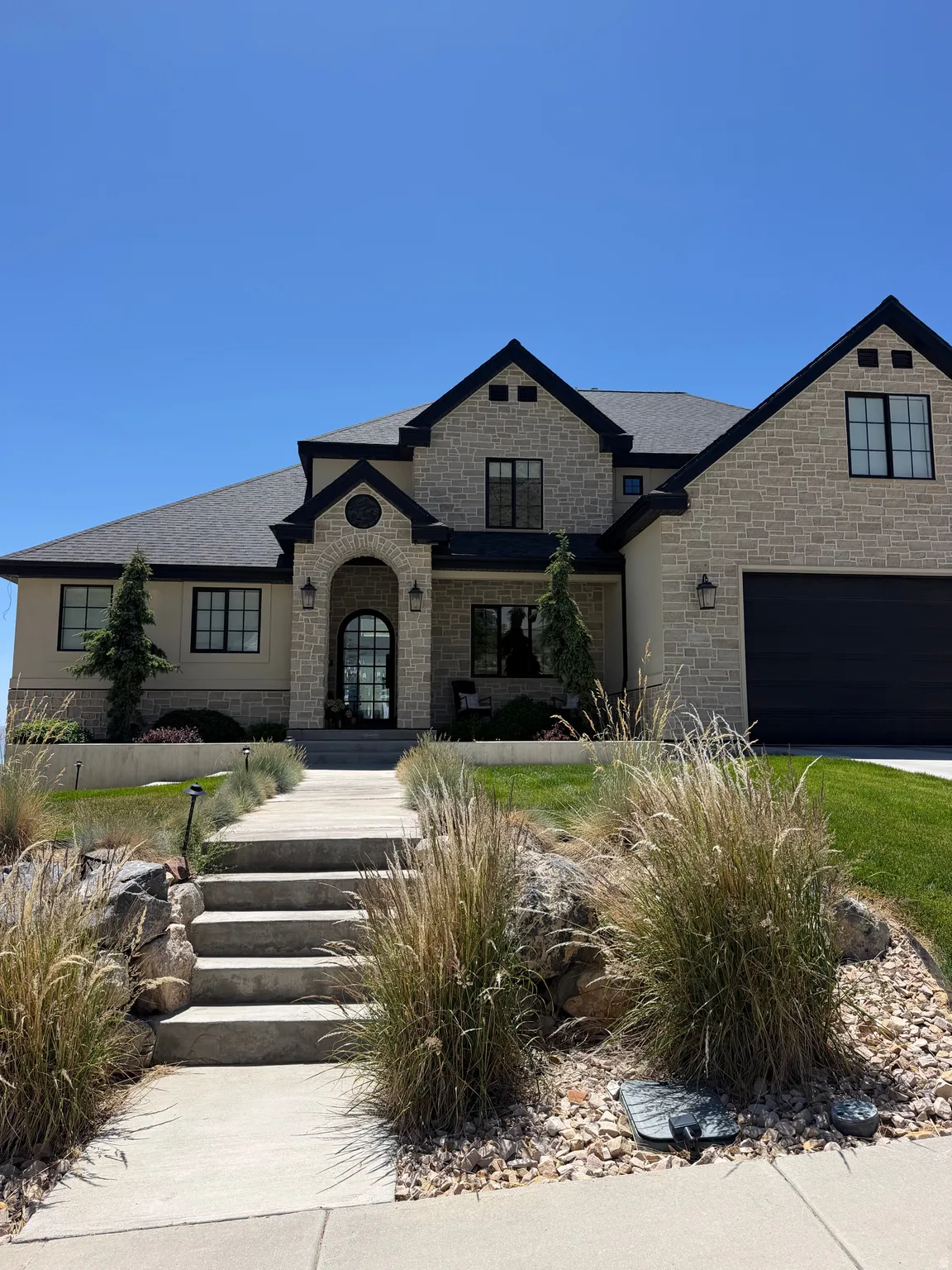 Stone facade residence featuring a prominent covered entry with arched details