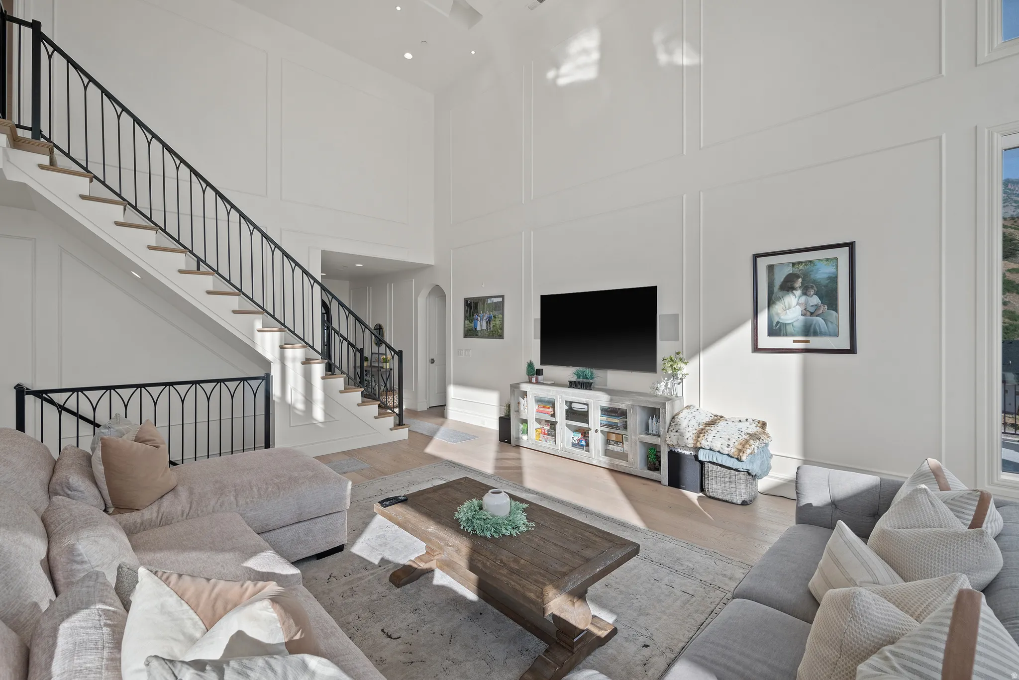 Two-story living area featuring a grand staircase with wrought iron balusters, recessed lighting, and wall paneling