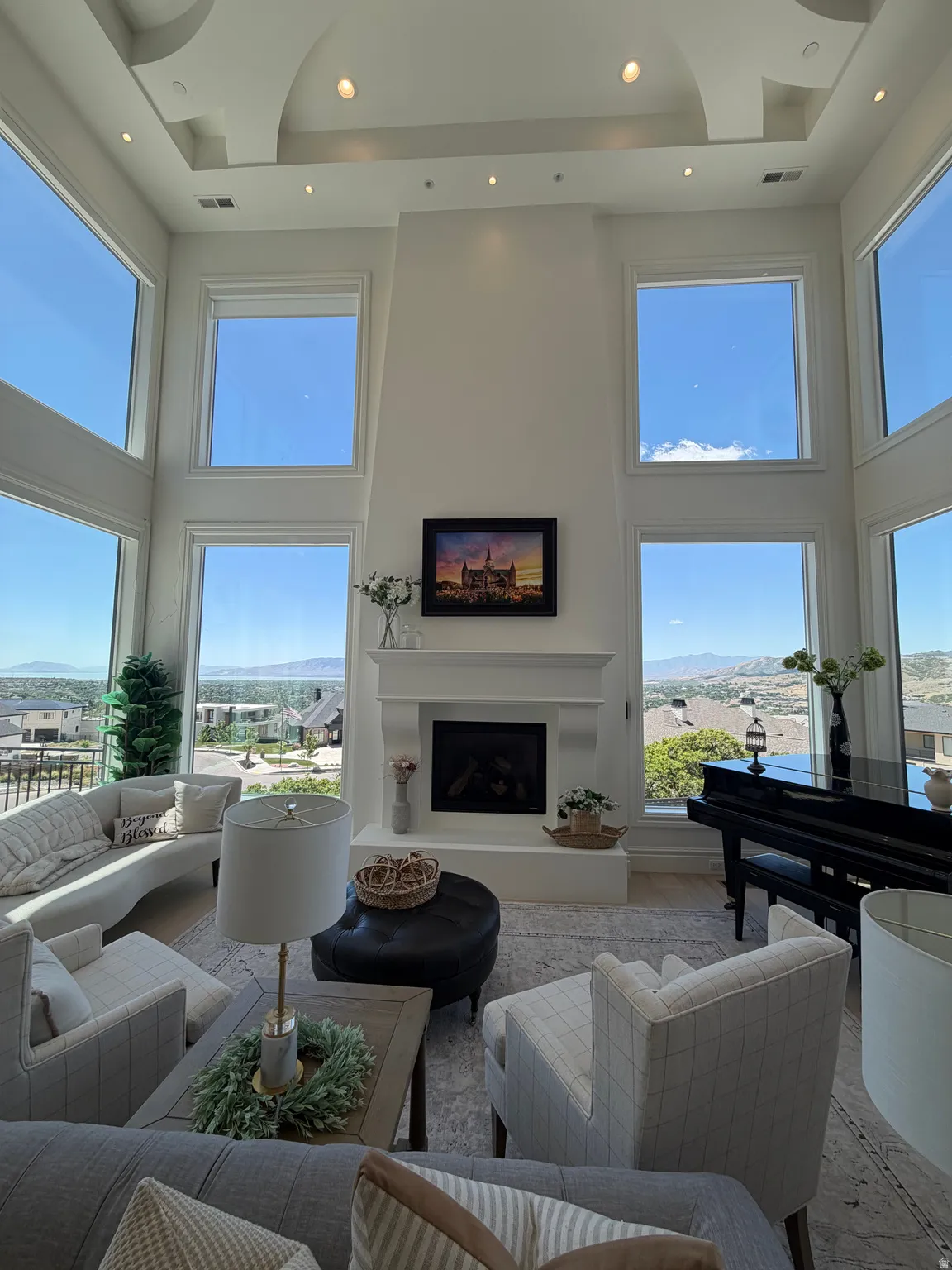 Two-story living room featuring a recessed ceiling, expansive windows, a fireplace with a mantel, and recessed lighting