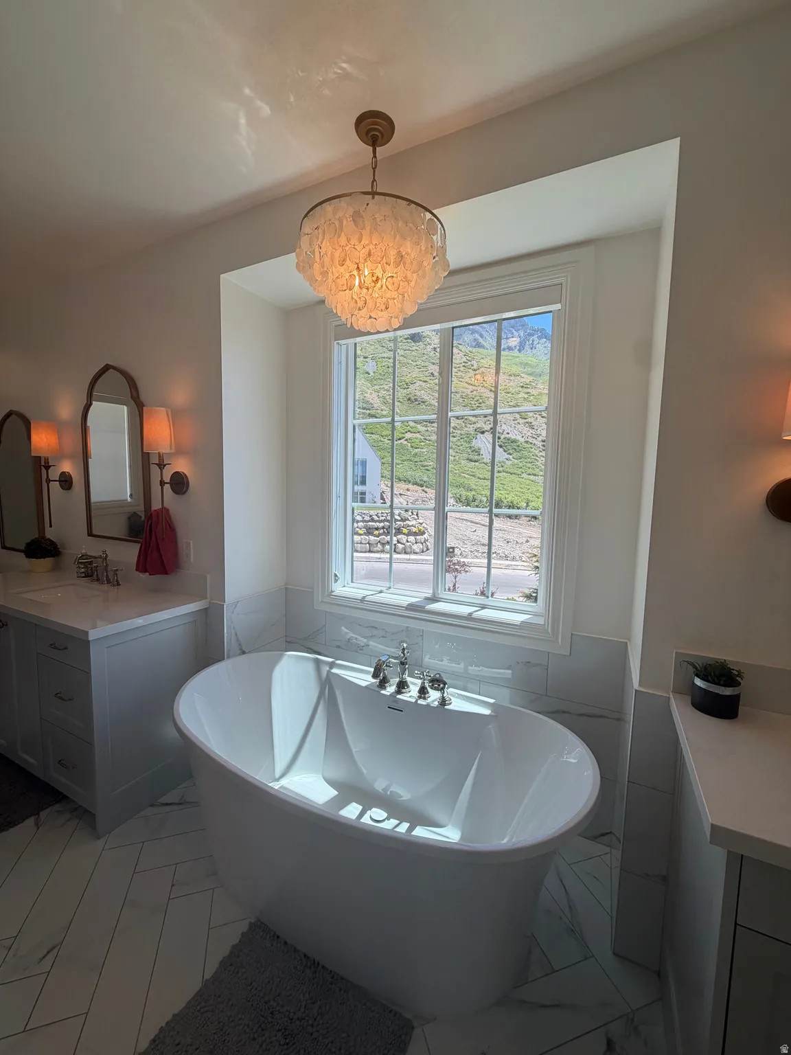 Freestanding soaking tub with polished chrome fixtures, set against a window with mountain scenery