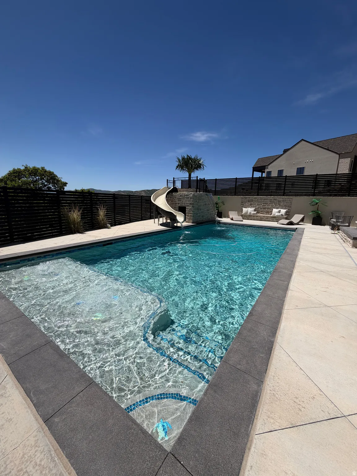 Rectangular swimming pool with a stone slide feature and integrated steps