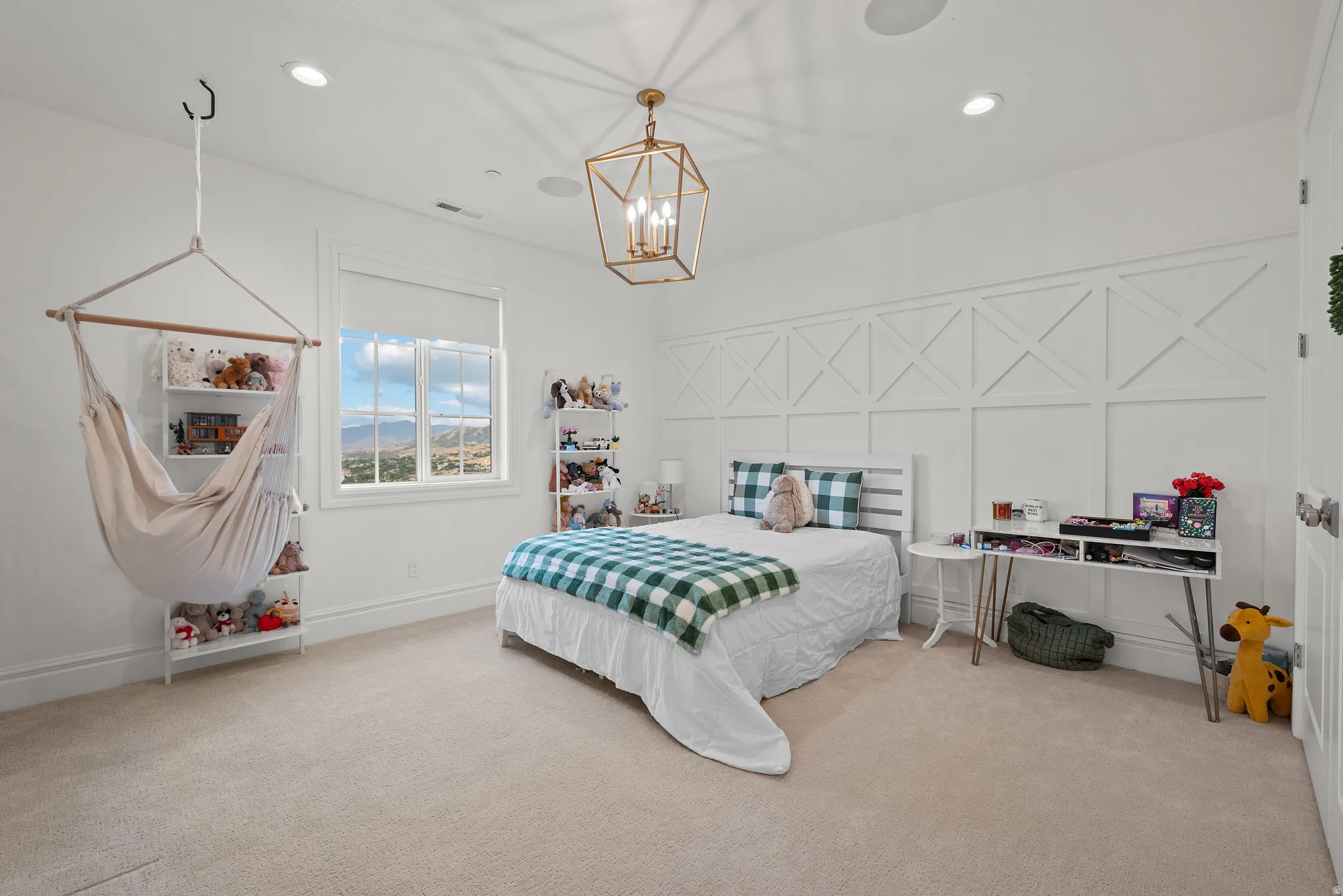 Bright interior space featuring a window with expansive distant scenery, recessed ceiling lighting, a decorative chandelier, and a paneled accent wall