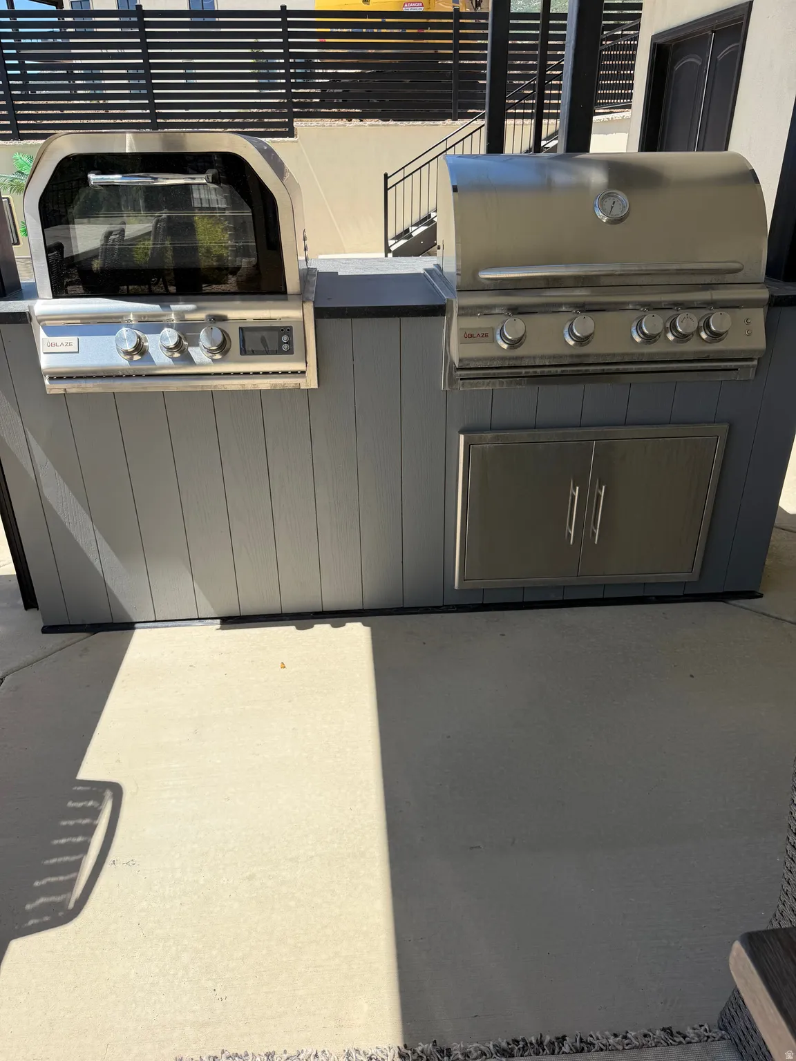 Outdoor kitchen featuring a built-in stainless steel grill, integrated oven, and stainless steel cabinet storage