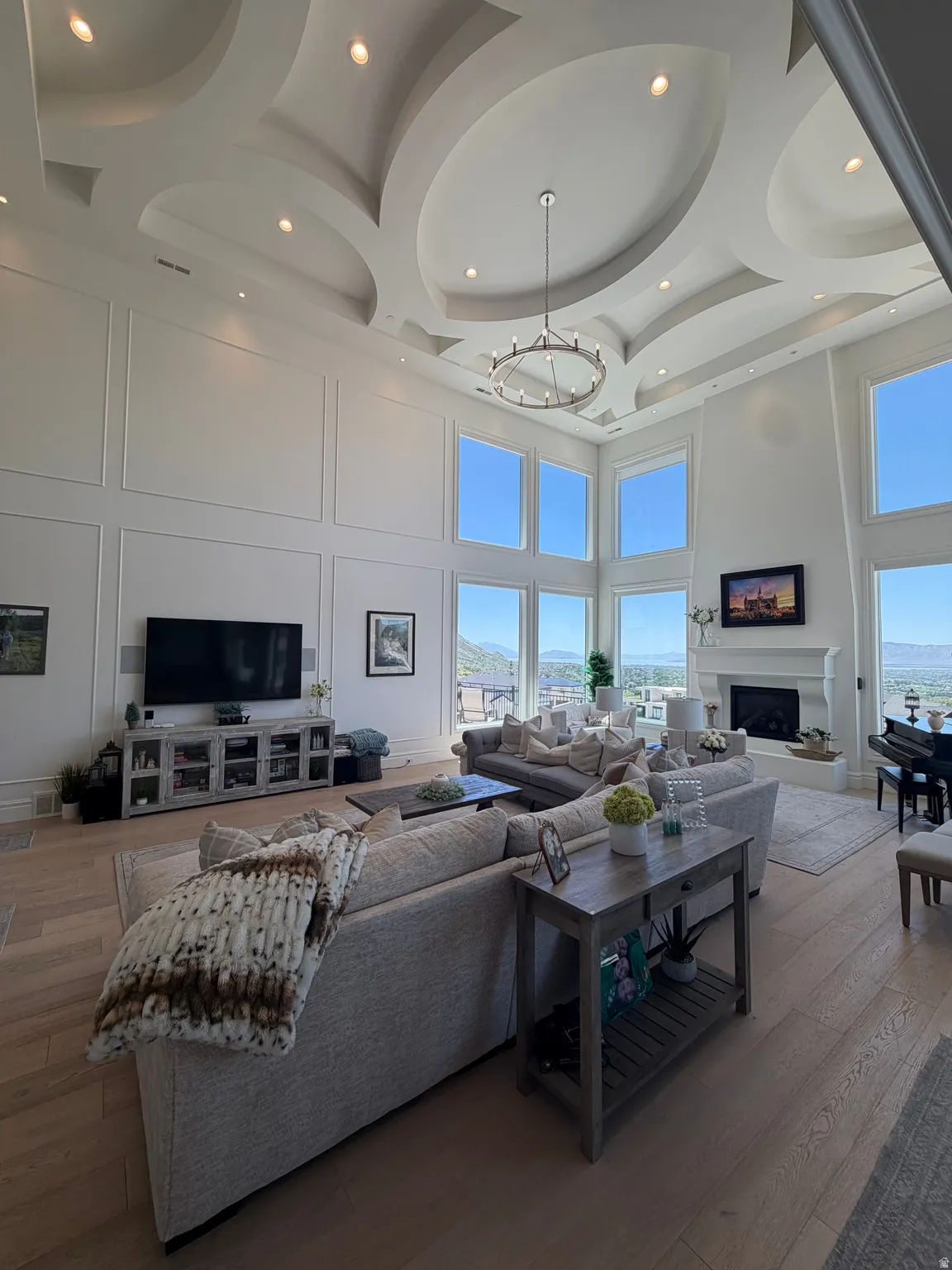 Two-story living area featuring a coffered ceiling with recessed lighting and a chandelier