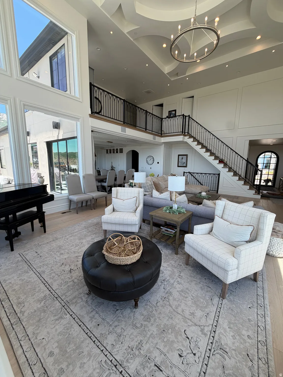 Grand living space featuring high ceilings, a decorative coffered ceiling detail, and a large circular chandelier