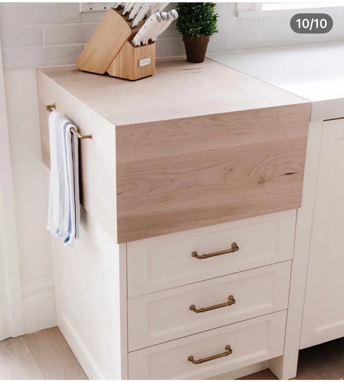 Light wood-finish countertop featuring a brass towel bar
