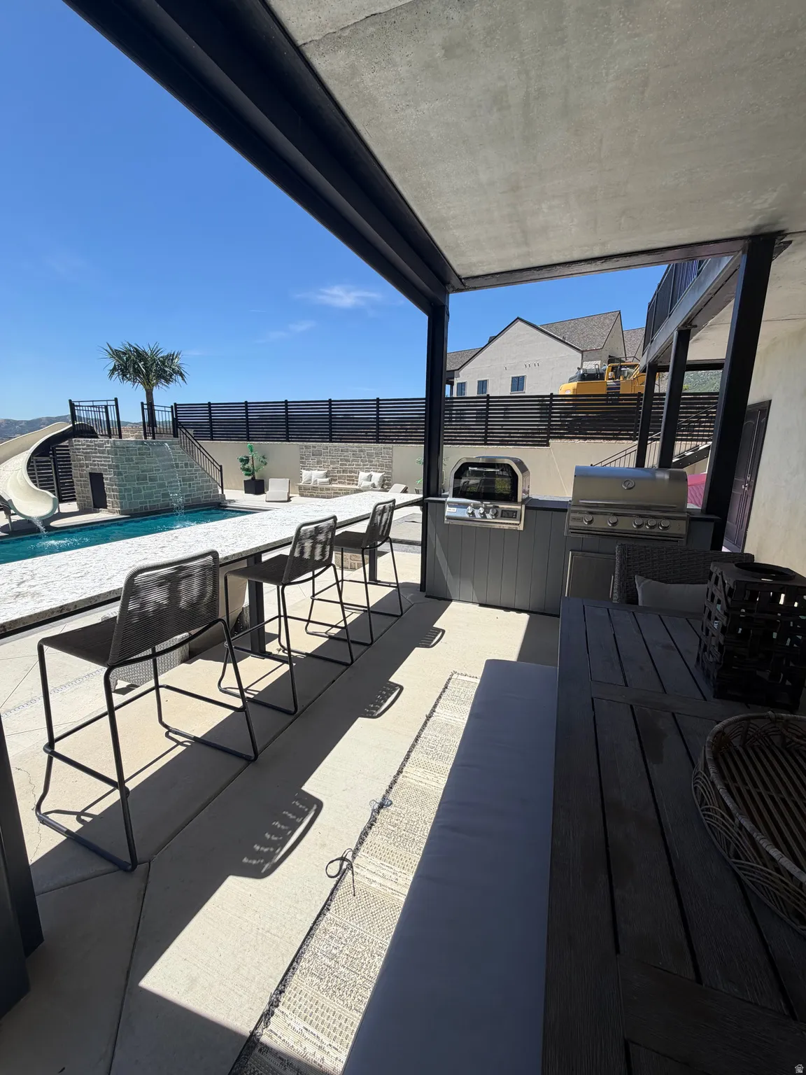 Covered outdoor kitchen featuring a built-in grill and counter seating