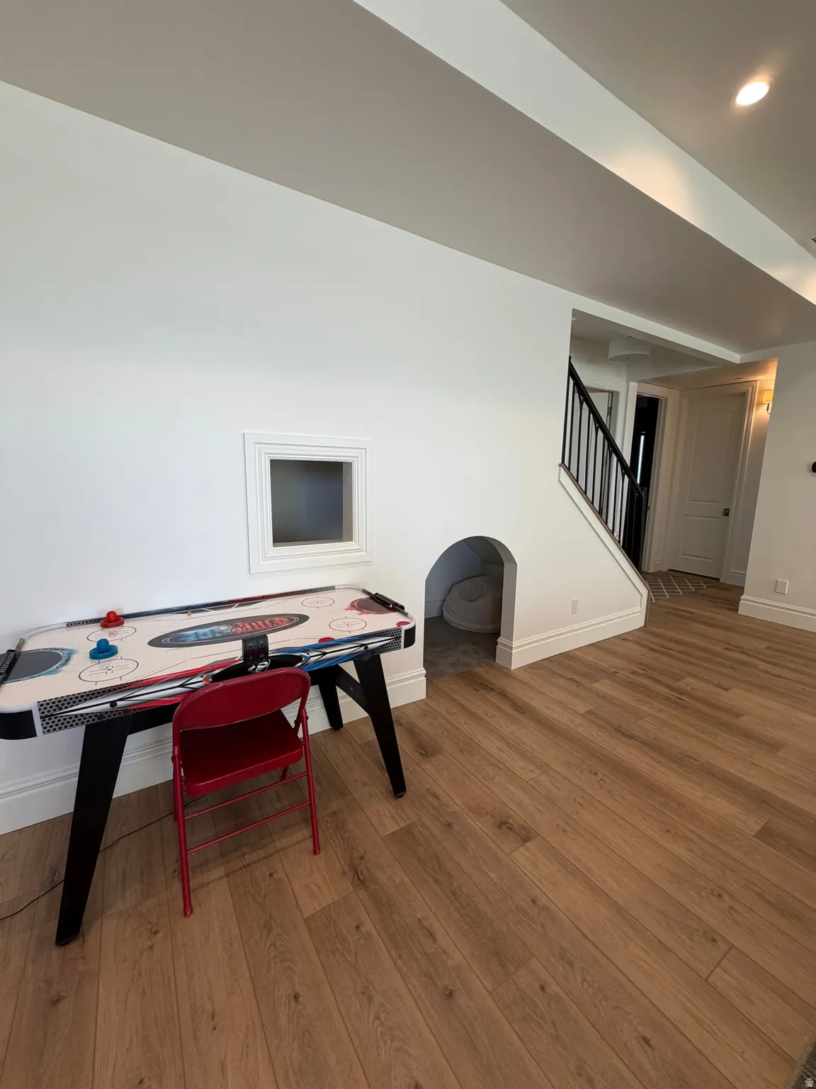 Open area featuring wood-finish flooring, white baseboards, and a built-in window niche