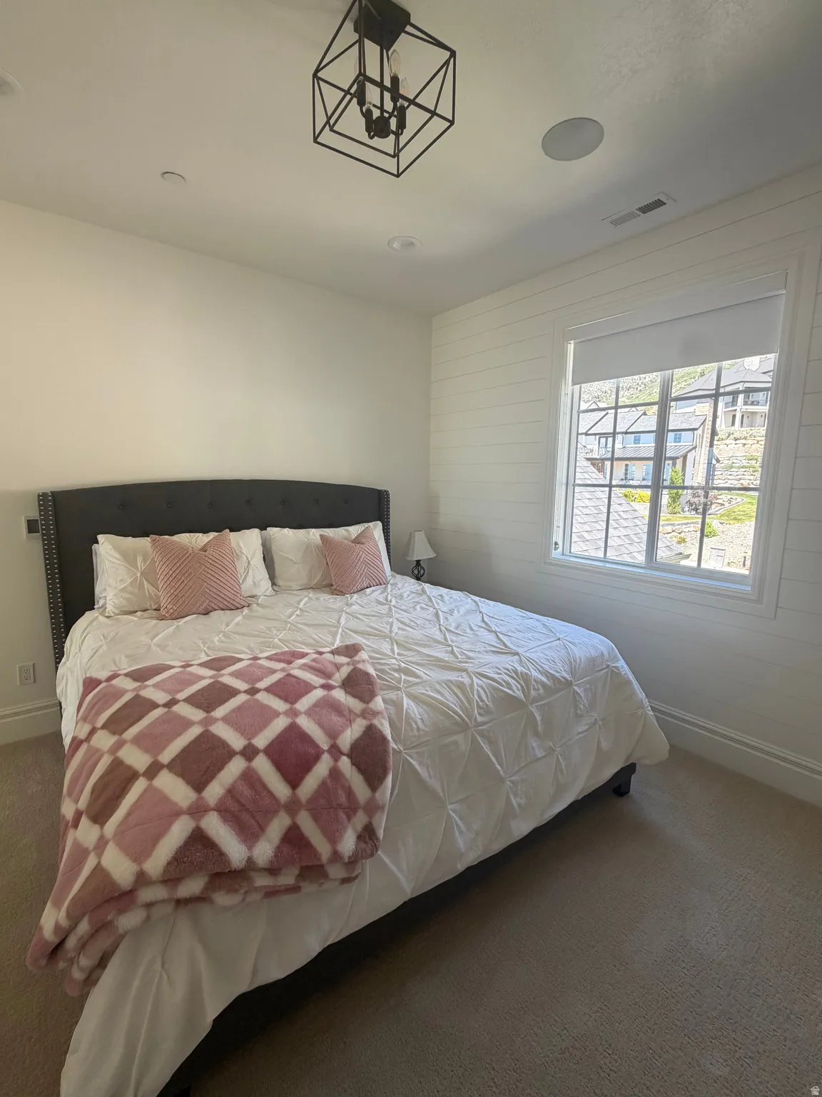 Bedroom featuring carpet flooring and a window with shiplap accent wall