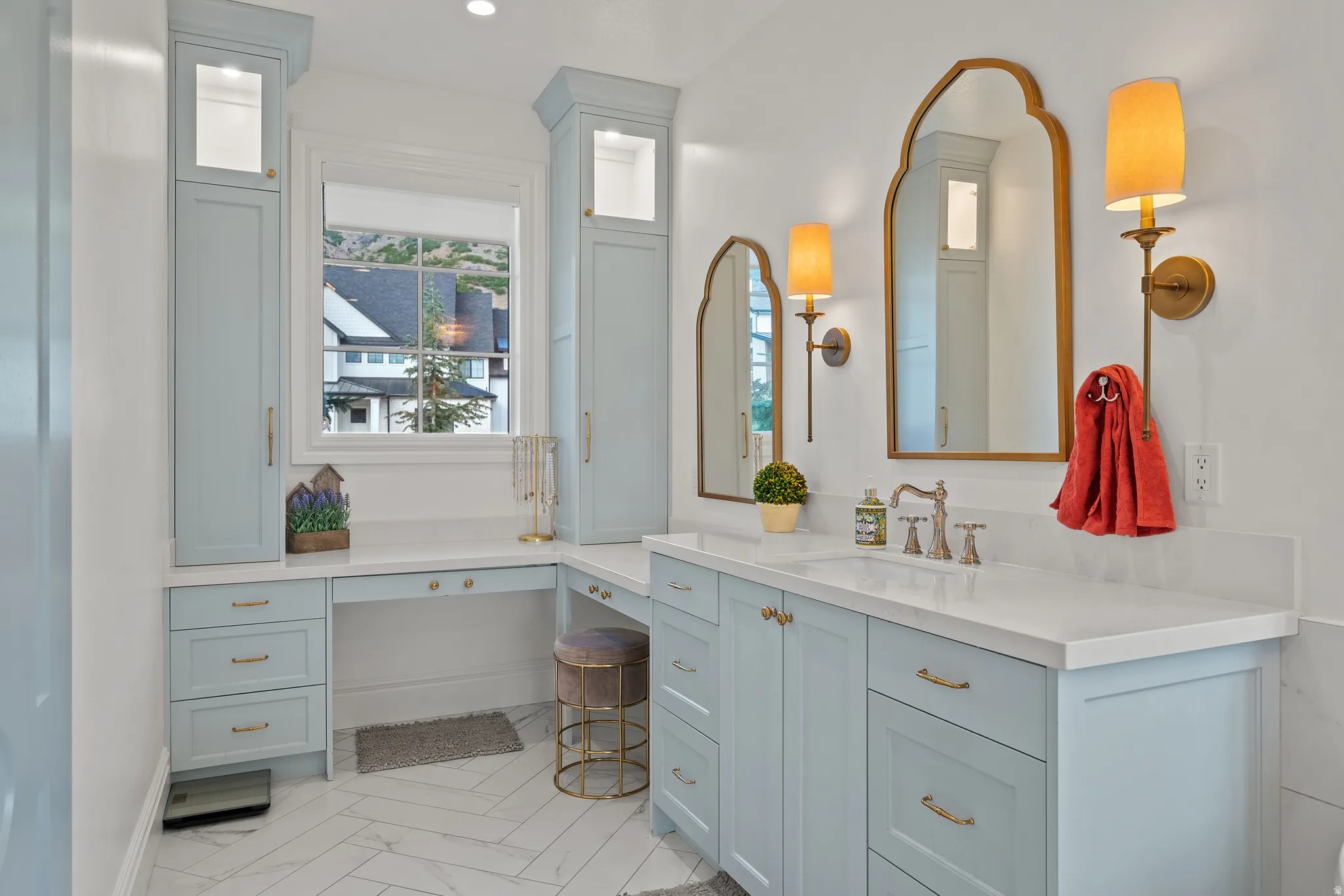 Bathroom featuring light blue cabinetry, dual gold-framed arched mirrors, and white countertops