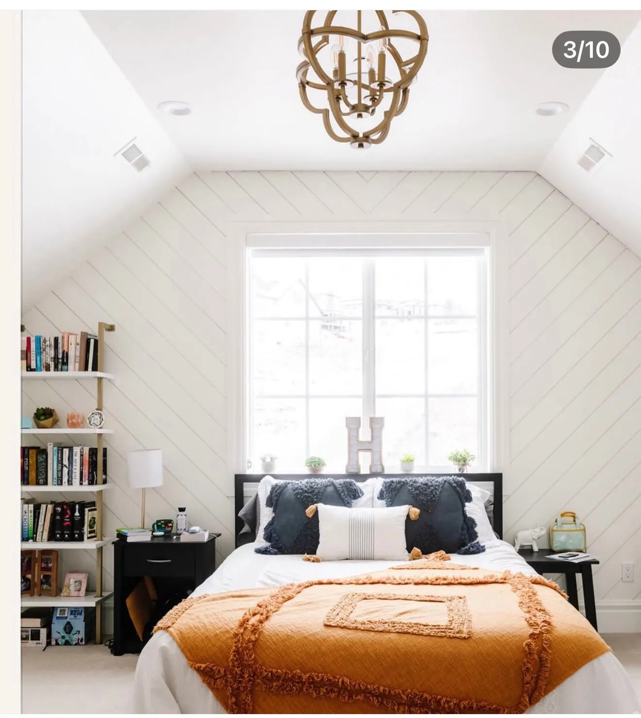 Sloped ceiling room featuring white shiplap walls, a large window with white trim, and a decorative wood-finish chandelier