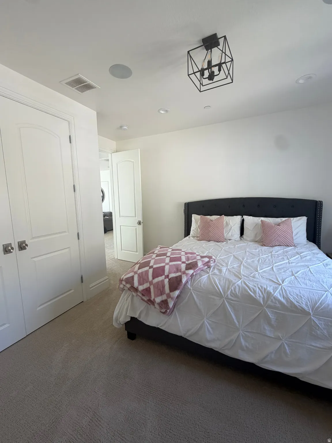 Carpeted room featuring white walls, a black geometric chandelier, recessed lighting, and a built-in ceiling speaker