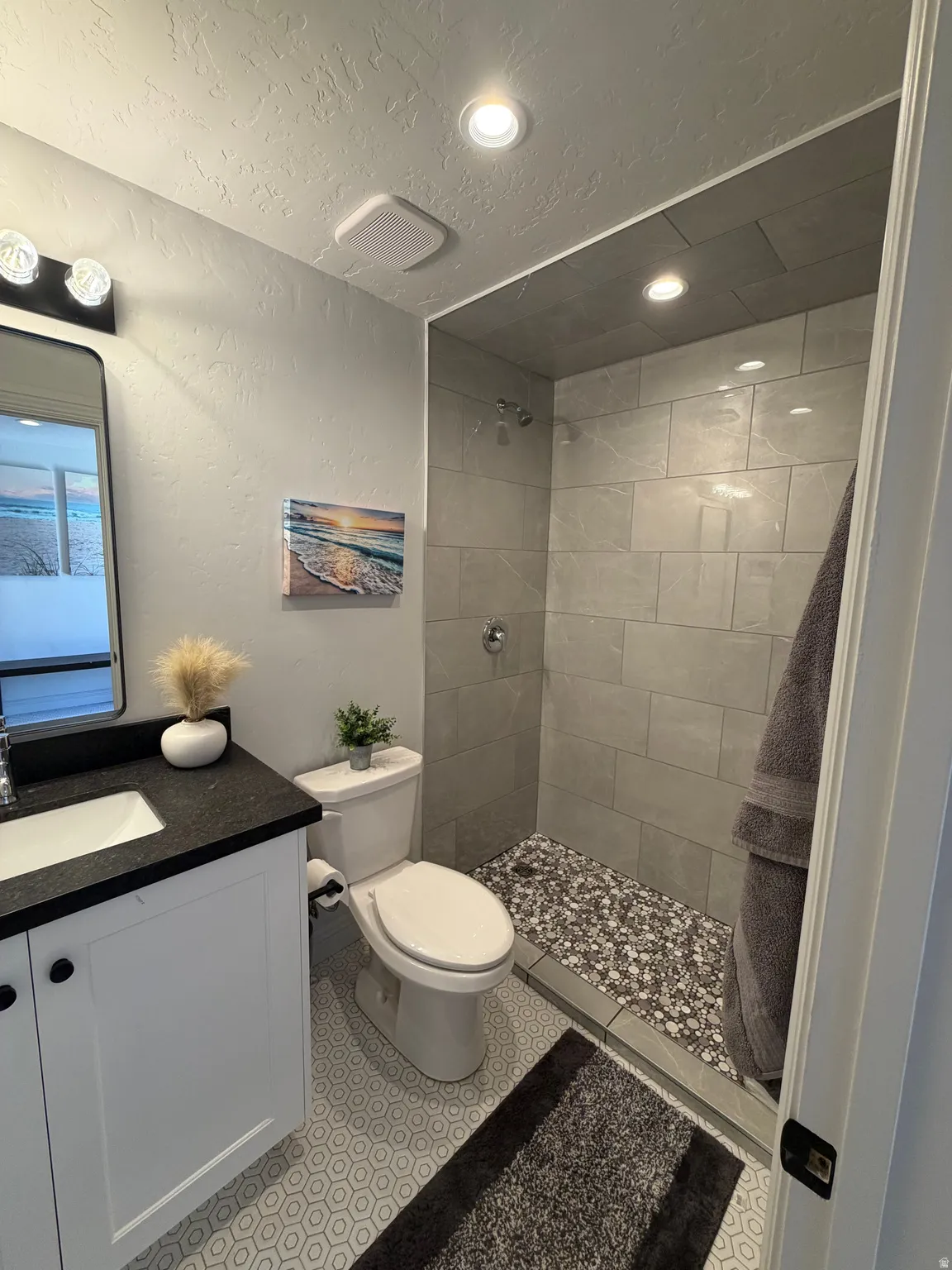 Contemporary bathroom featuring a walk-in shower with pebble tile flooring and large format wall tiles