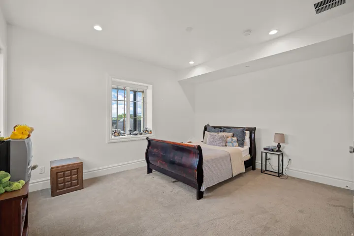 Spacious room featuring neutral carpeting, recessed lighting, and a window with white trim