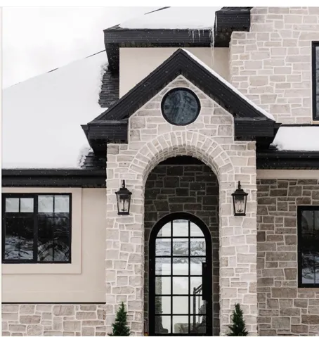 Stone facade featuring an arched entryway with a black grid-patterned door