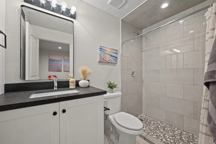Bathroom featuring a white vanity with black countertop, rectangular undermount sink, and a framed mirror