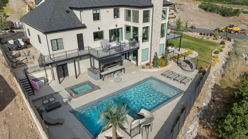 Expansive backyard oasis featuring a rectangular swimming pool, integrated spa, and an outdoor kitchen area