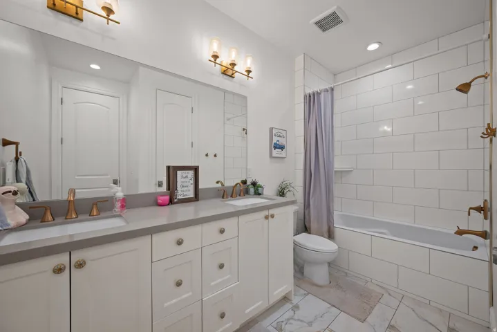 Bathroom featuring a dual vanity with light gray countertops and white cabinetry