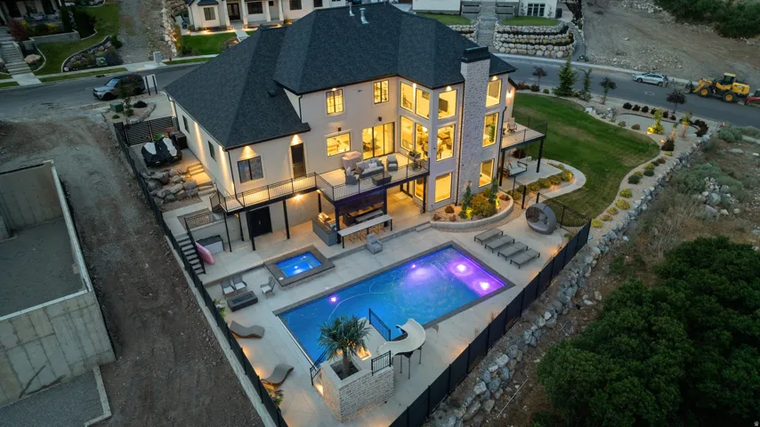 Multi-level residence featuring a dark shingle roof, light-colored siding, and extensive window arrays