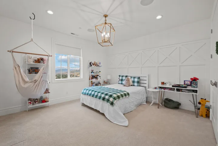 Bright interior space featuring a window with expansive distant scenery, recessed ceiling lighting, a decorative chandelier, and a paneled accent wall