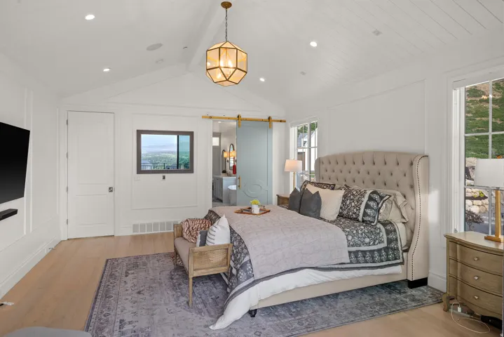 Vaulted shiplap ceiling with recessed lighting and a central geometric pendant fixture