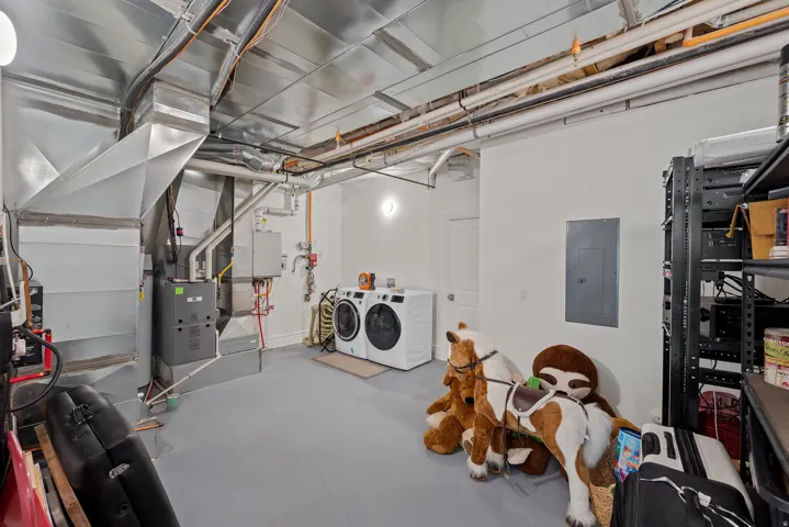 Laundry area featuring a stackable washer and dryer, utility sink, and overhead lighting