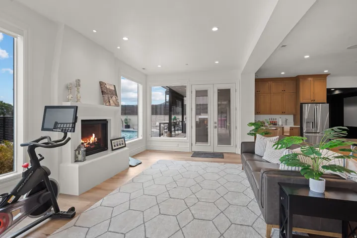 Living area with a built-in fireplace, light wood-finish flooring, recessed lighting, and large windows