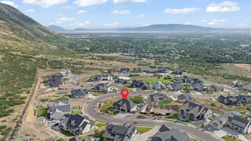 Aerial perspective of a hillside residential development featuring a mountain backdrop and distant body of water